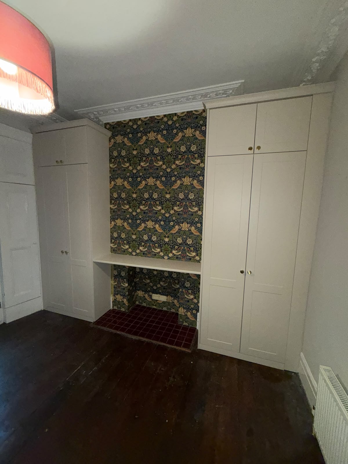 Custom fitted storage surrounding a wallpapered desk alcove