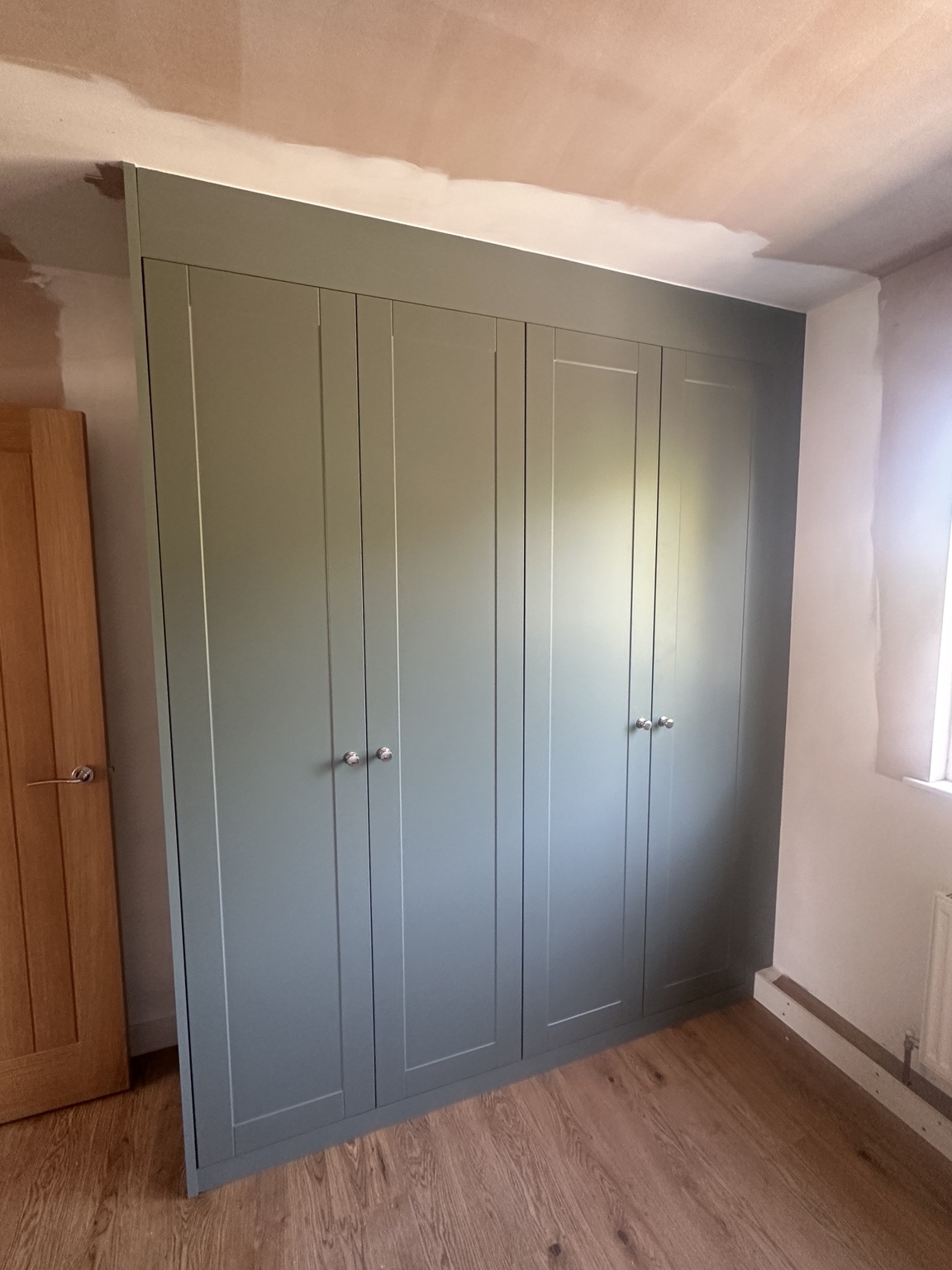 Completed full-height green fitted wardrobe with shaker doors
