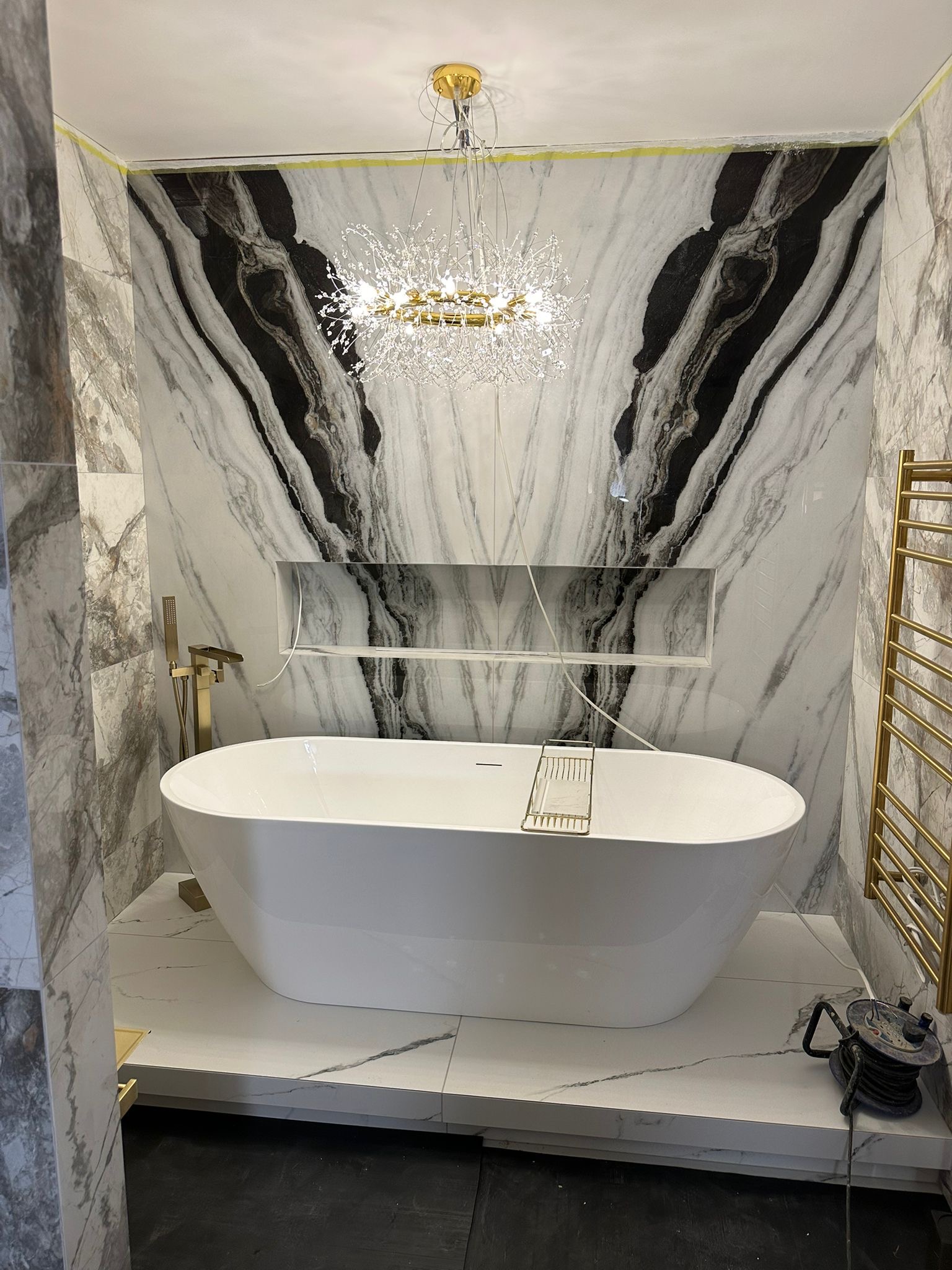 Luxury marble-effect bathroom with freestanding bath and fitted niche